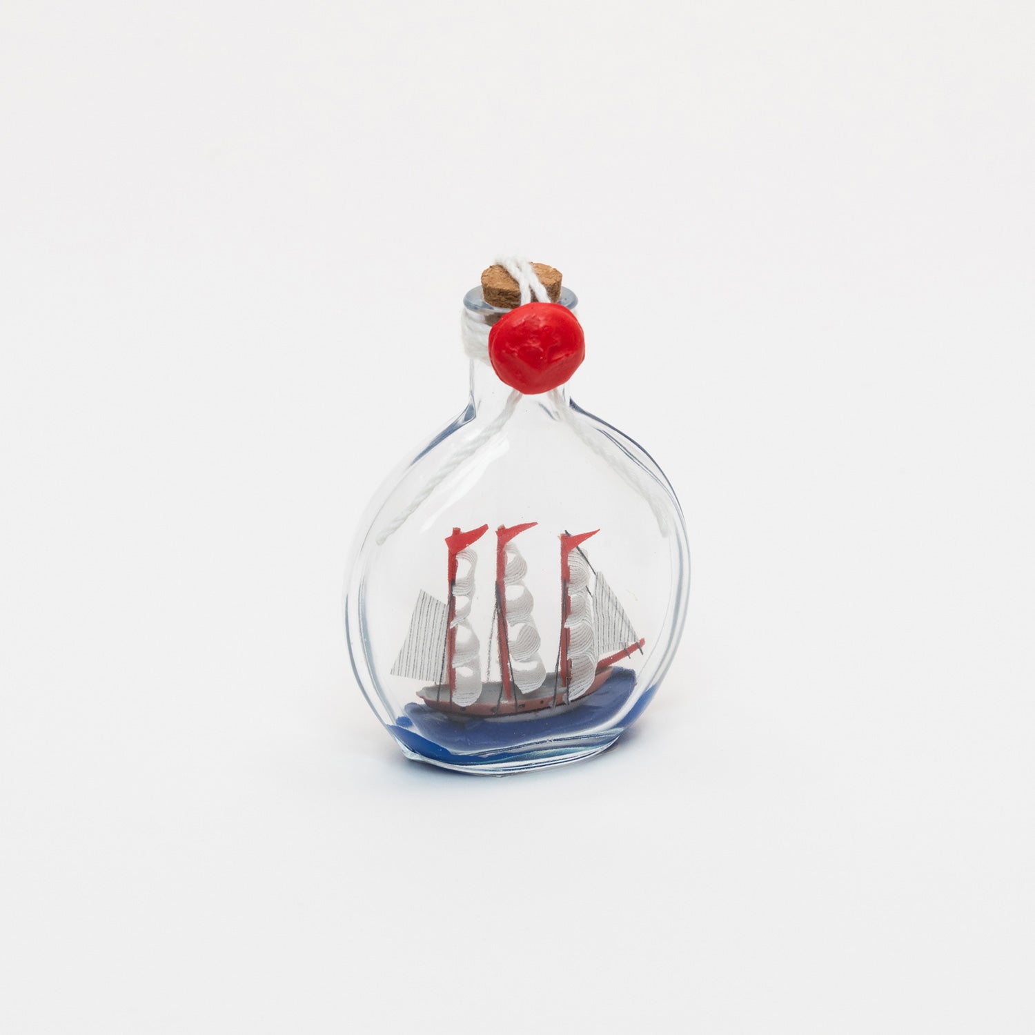 A photo of a small ship in a bottle, on a white background.