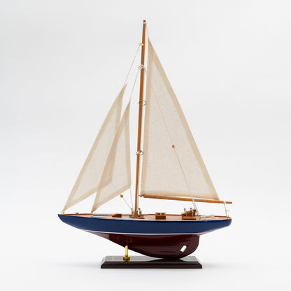 A side view of the 36cm J Class Yacht with a burgundy and blue hull and cream coloured sails. 