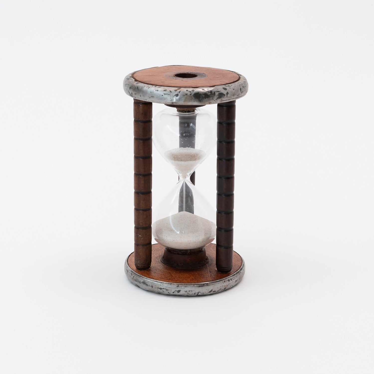 White sand falling through the glass egg timer with a wooden and metal bobbin case.