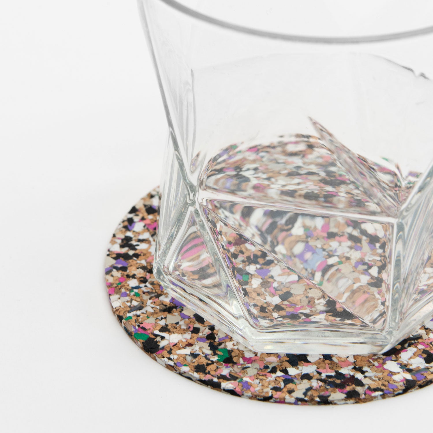 One of the multi-coloured Beach Clean Coasters with a clear glass on it.