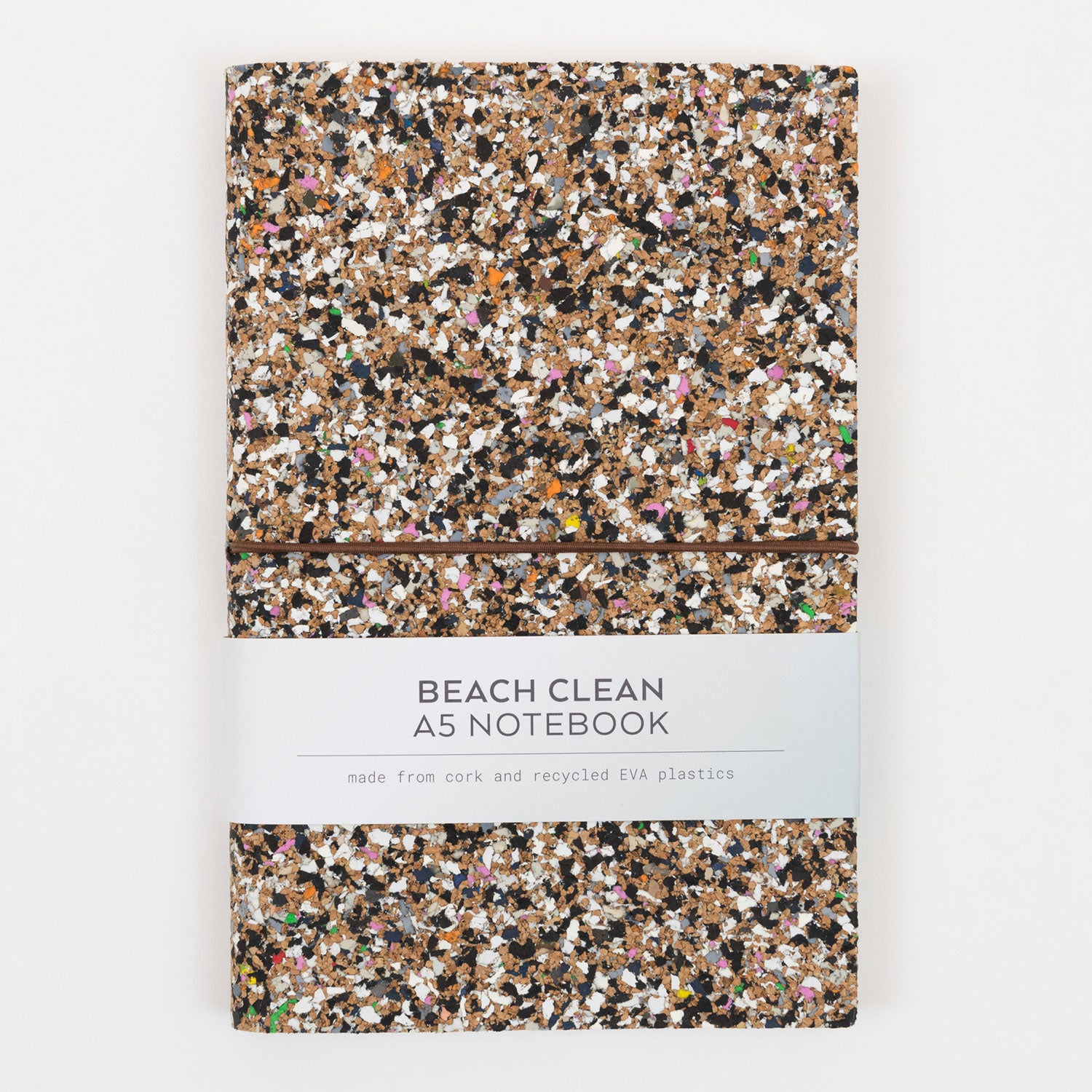 Front of the Beach Clean Cork Notebook. The cover is speckled with lots of different colours. The photo shows the paper packaging going around the notebook.