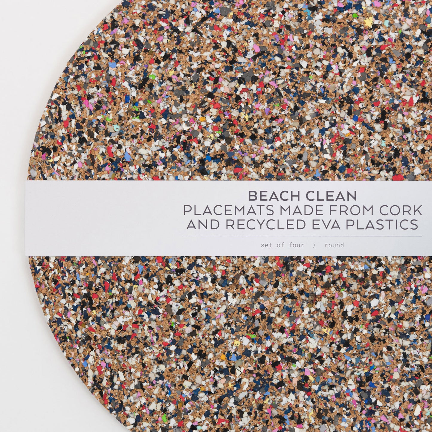 Close-up top down view of the Beach Clean Placemat Set with the packaging strip going across the middle of the circular placemats.