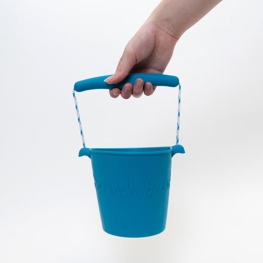 sea blue silicone bucket being held by the handle