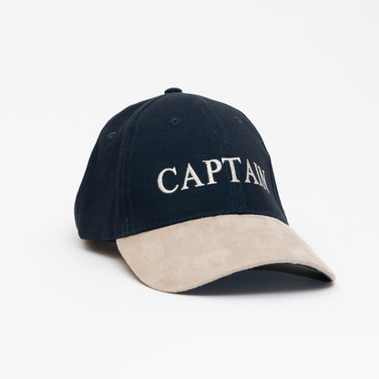 A black cap with a beige peak, with the word 'Captain' written on the front. Photographed on a white background.