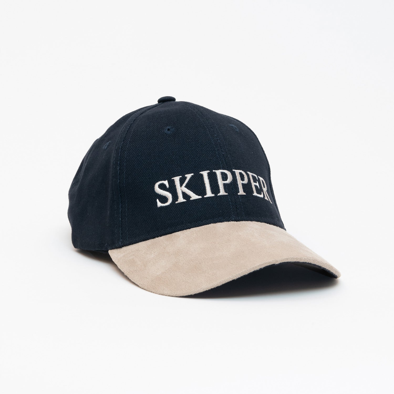 A black hat with beige peak, and the word 'Skipper' sewn onto the front. Photographed on a white background.