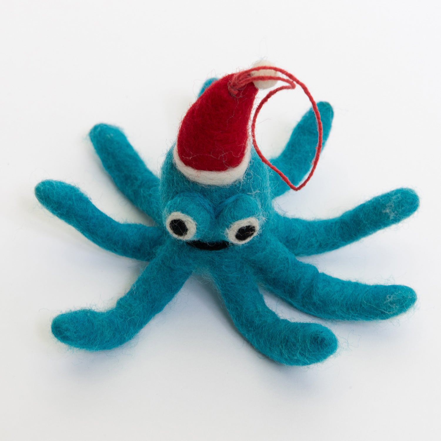 A Christmas decoration pictured on a white background. The decoration is a felt blue octopus wearing a red Christmas hat, smiling.