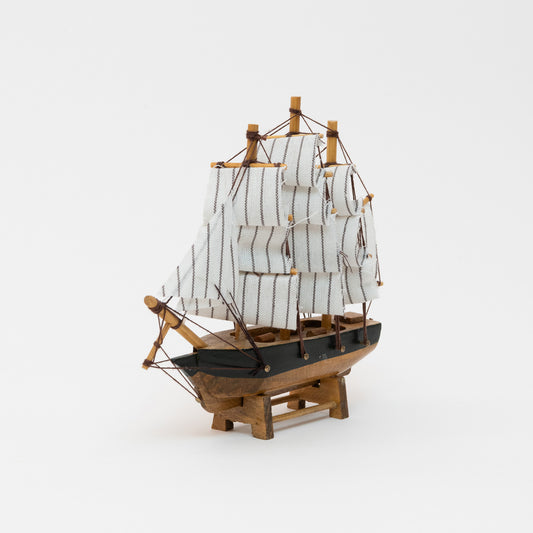 Front and side view of the model clipper with wooden hull and white stripy sails.