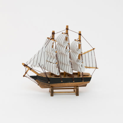 Side view of the model clipper with wooden hull and white stripy sails.