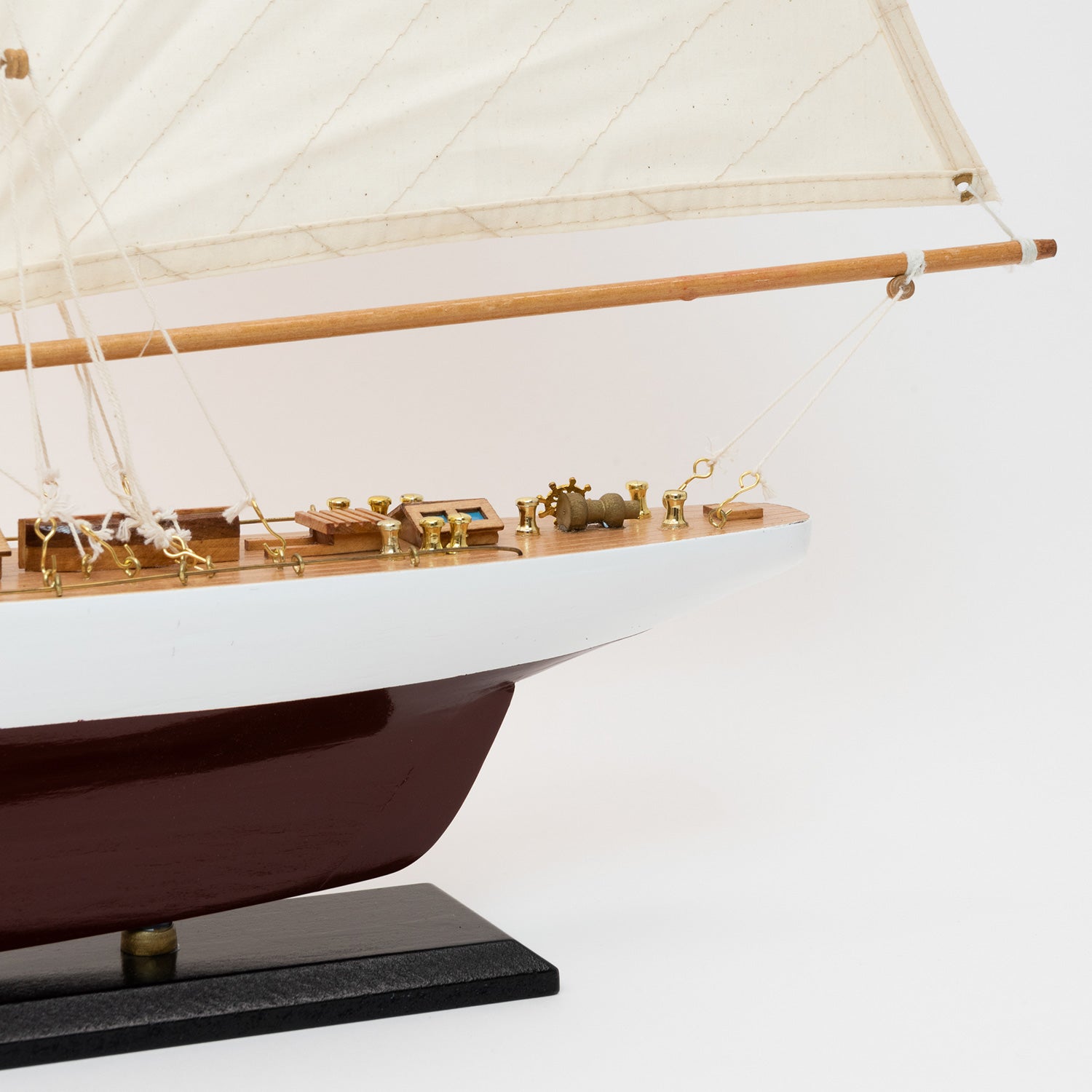 Close-up view of the model Colombia Yacht's stern with white and burgundy hull and cream coloured sails.