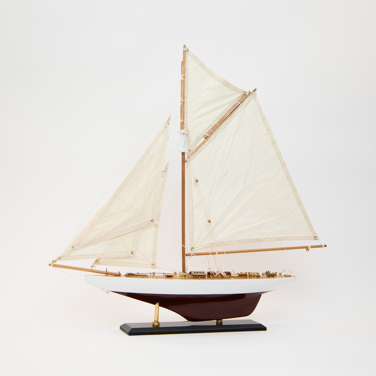 Side view of the model Colombia Yacht with white and burgundy hull and cream coloured sails.