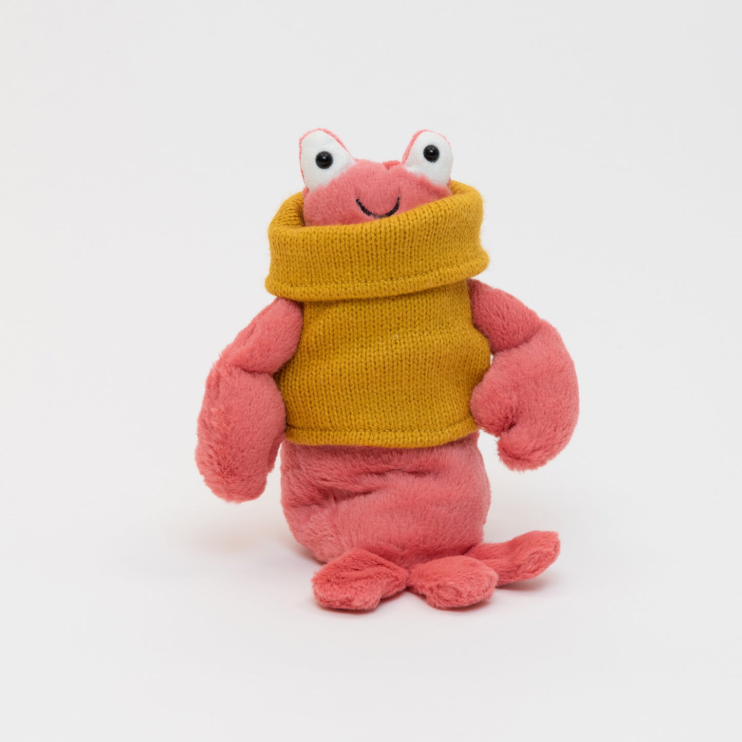 A pink plush lobster smiling and wearing a yellow jumper. Pictured on a white background.