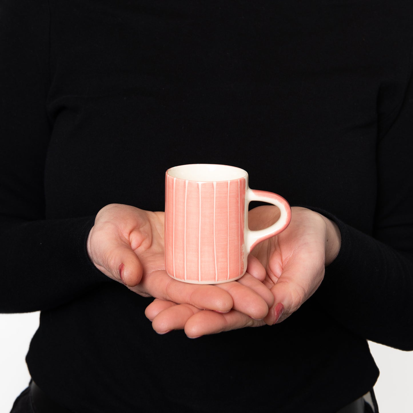 Model holding Espresso cup with pink wash with thin white vertical stripes