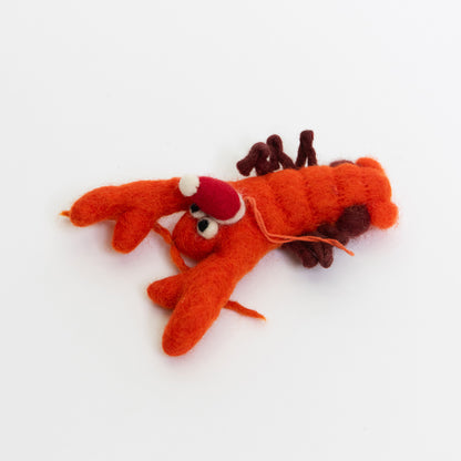 A Christmas lobster decoration on a white background. The decoration is an orange felt lobster wearing a red Christmas hat.