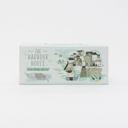 Top view of the box for the fish bottle opener featuring an illustration of the bottle opener and a seaside town and harbour.