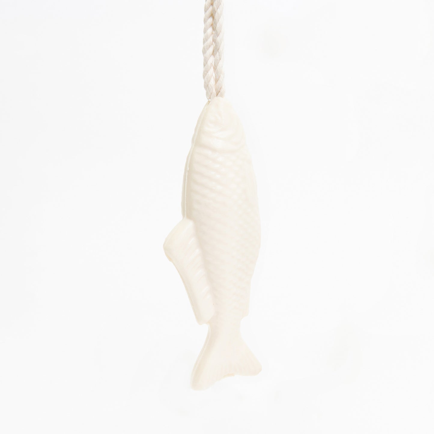 A white soap on a rope with a fish design, pictured on a white background.