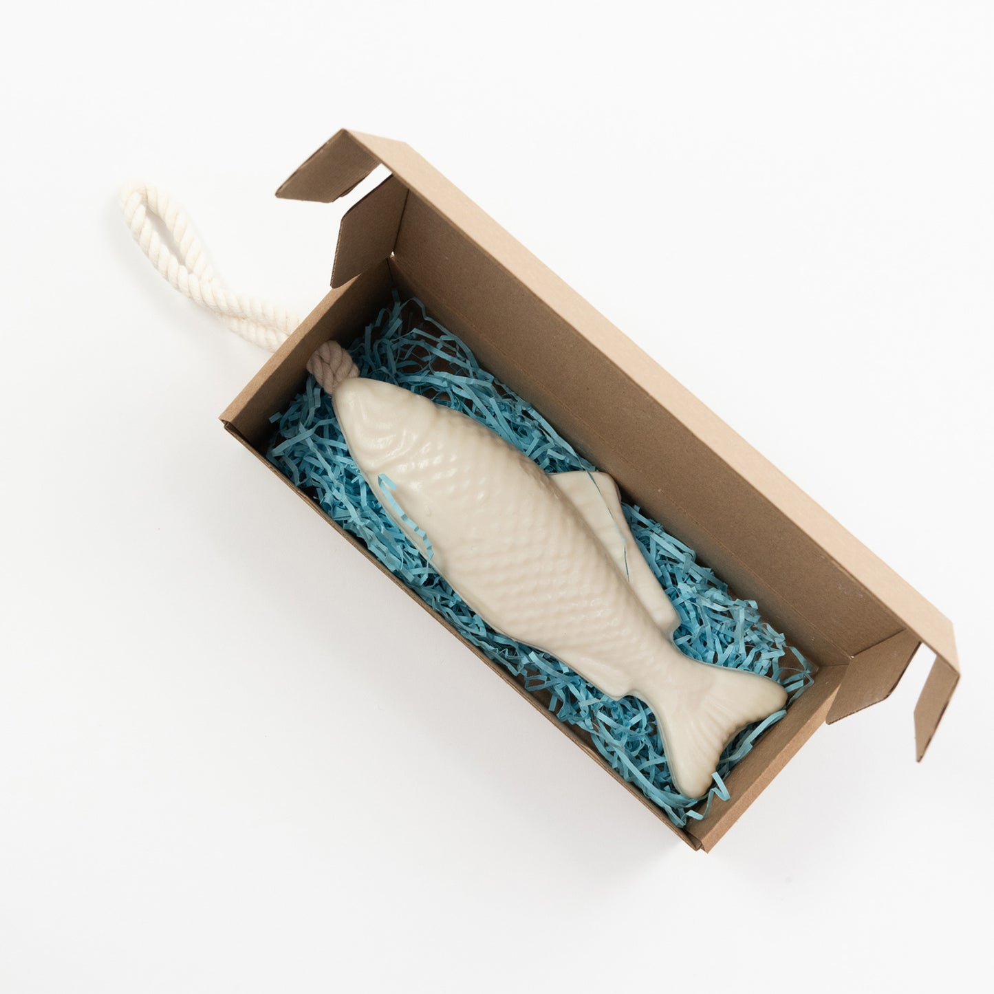 A white soap on a rope gift pictured in a cardboard gift box that contains blue tissue paper.