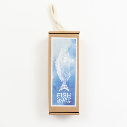 The box for a gift fish soap on a rope, pictured on a white background. The box is cardboard with a blue fish print on the front.