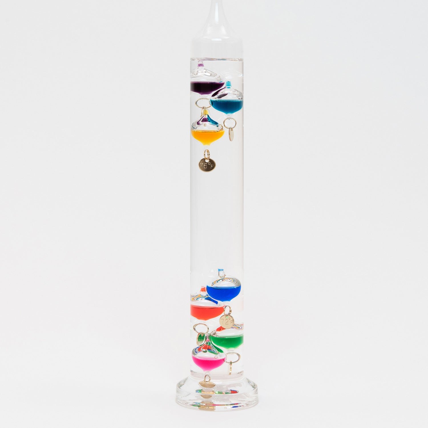 A close up of the Galileo Thermometer on a white background. The transparent thermometer has coloured globes floating within it.