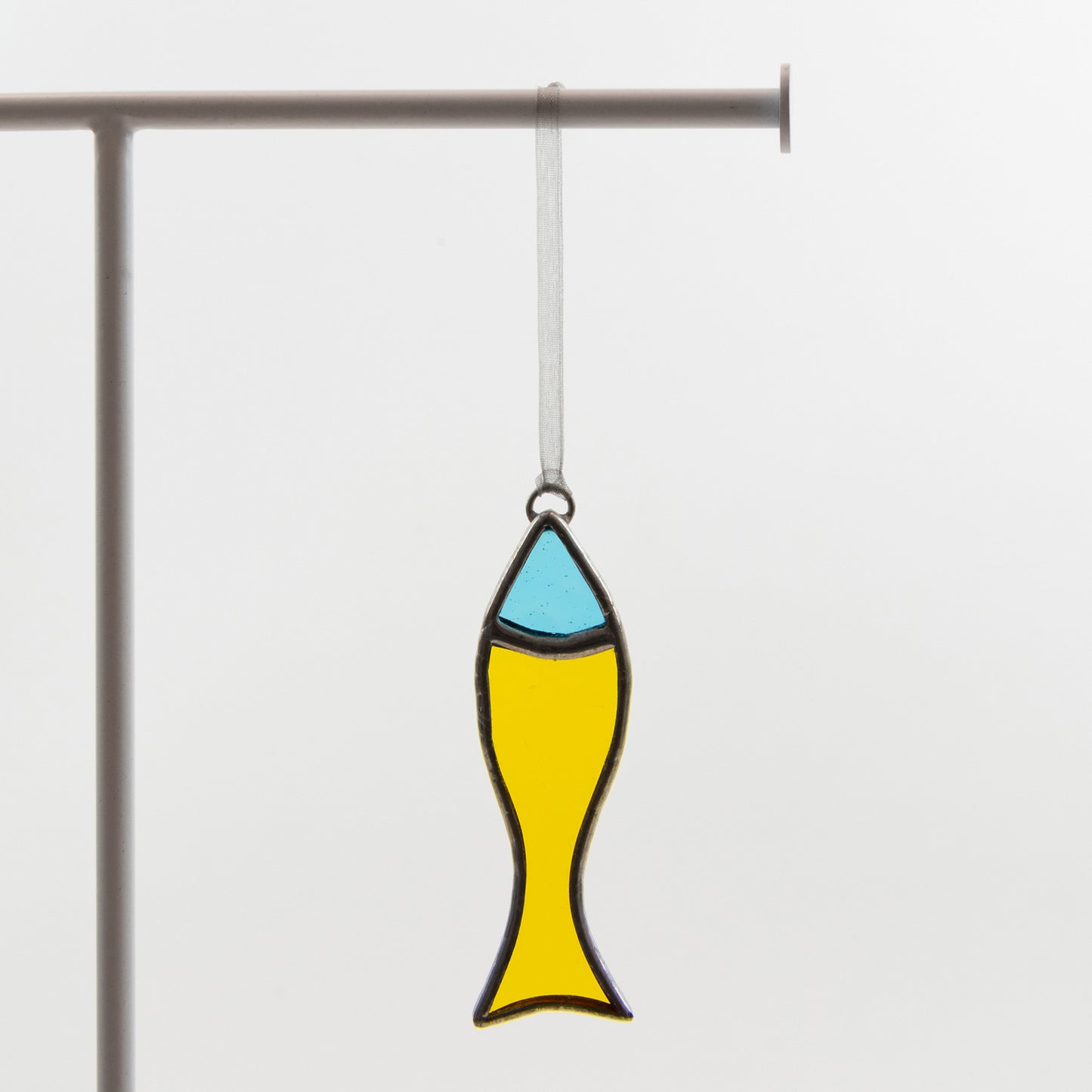 A stained glass effect fish decoration with ribbon to hang the decoration from. This fish was made using yellow and blue glass.