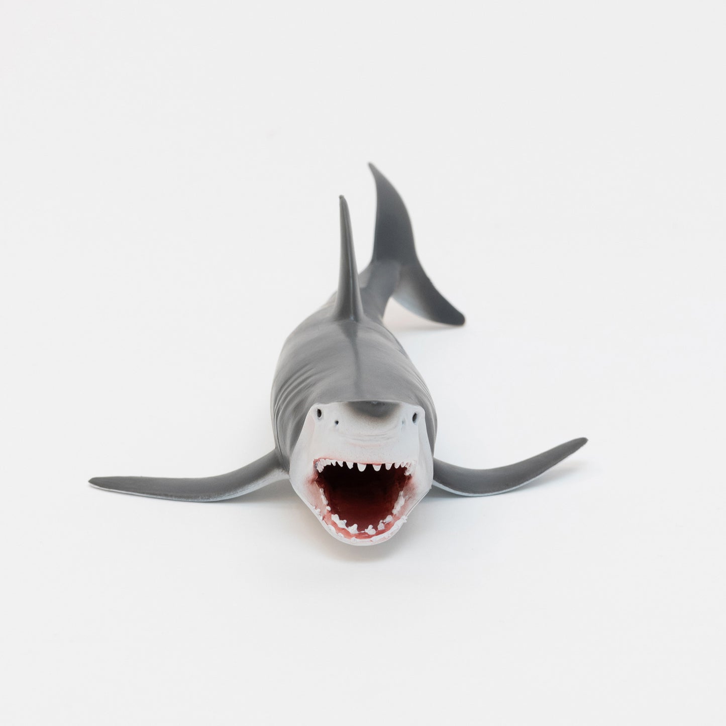 A plastic great white shark toy on a white background.