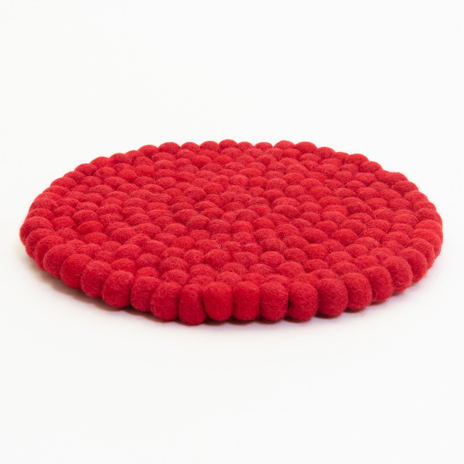 A red felt ball trivet pictured on a white background.