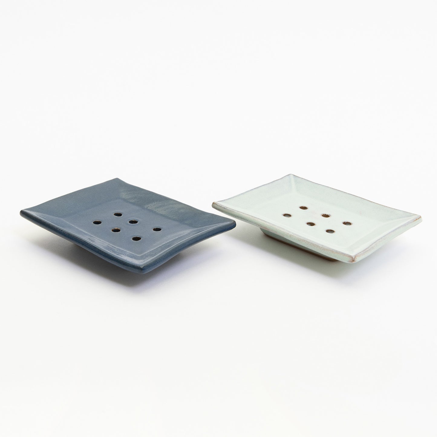 Cobalt blue and ice wash coloured stoneware soap dishes pictured on a white background.