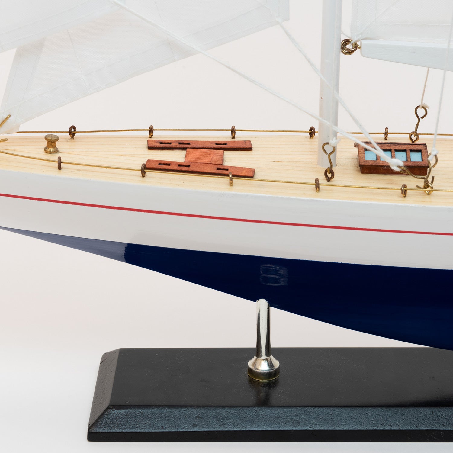View of the Model J Class Yacht's bow with white sails and a blue and white hull.