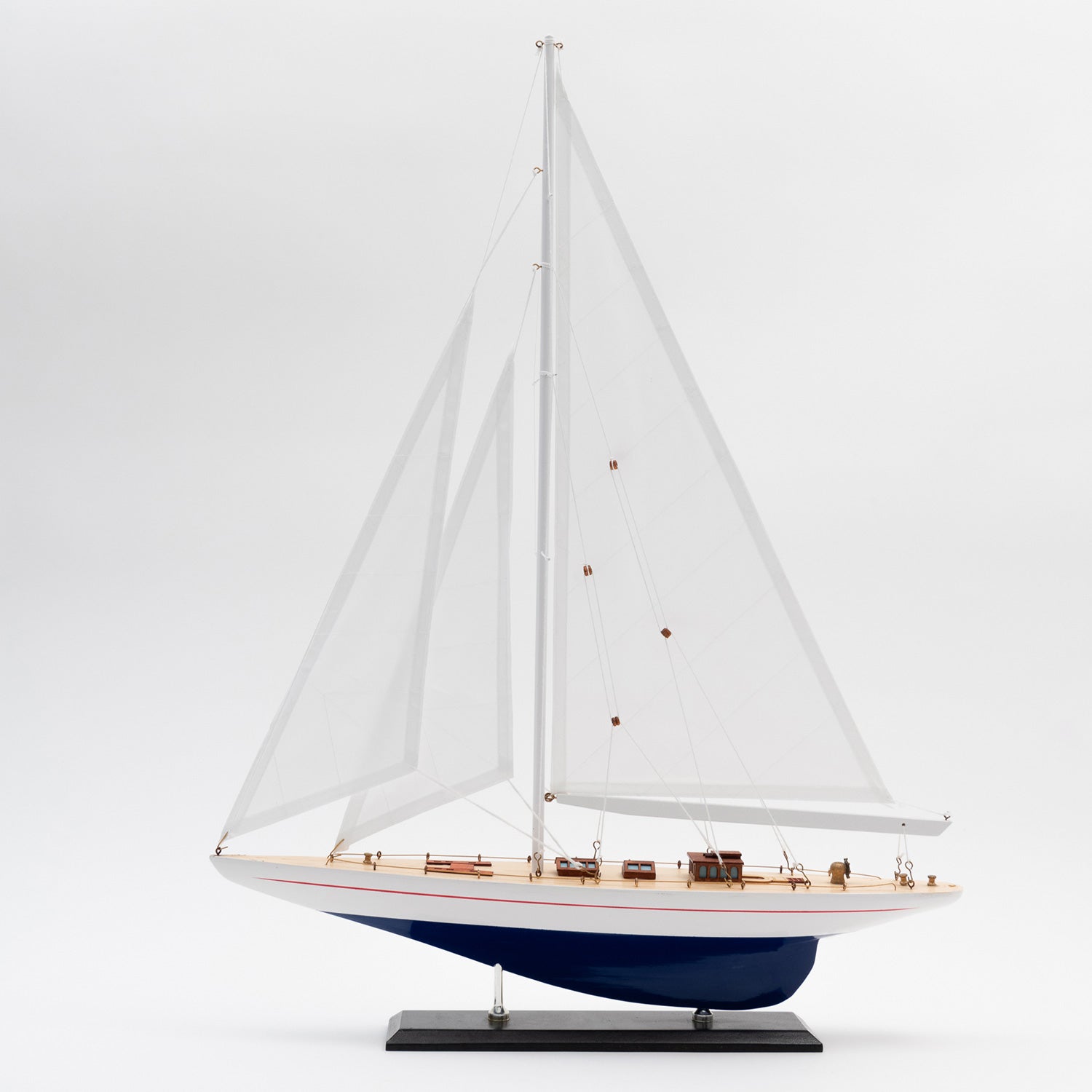 Full side view of the Model J Class Yacht with white sails and a blue and white hull.