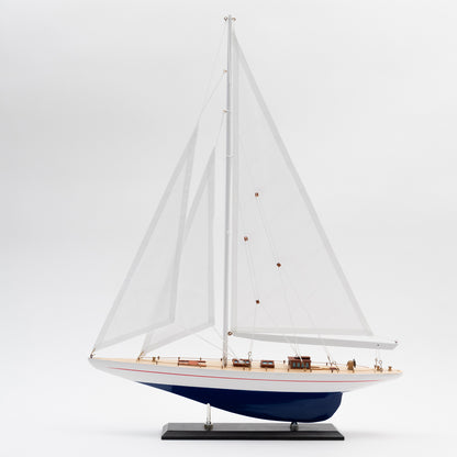 Full side view of the Model J Class Yacht with white sails and a blue and white hull.
