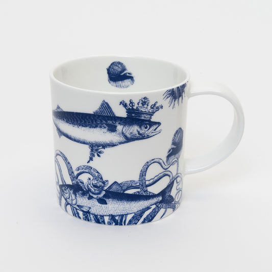 Blue and white image of fish wearing crown on a mug, shell printed on the inside of the mug