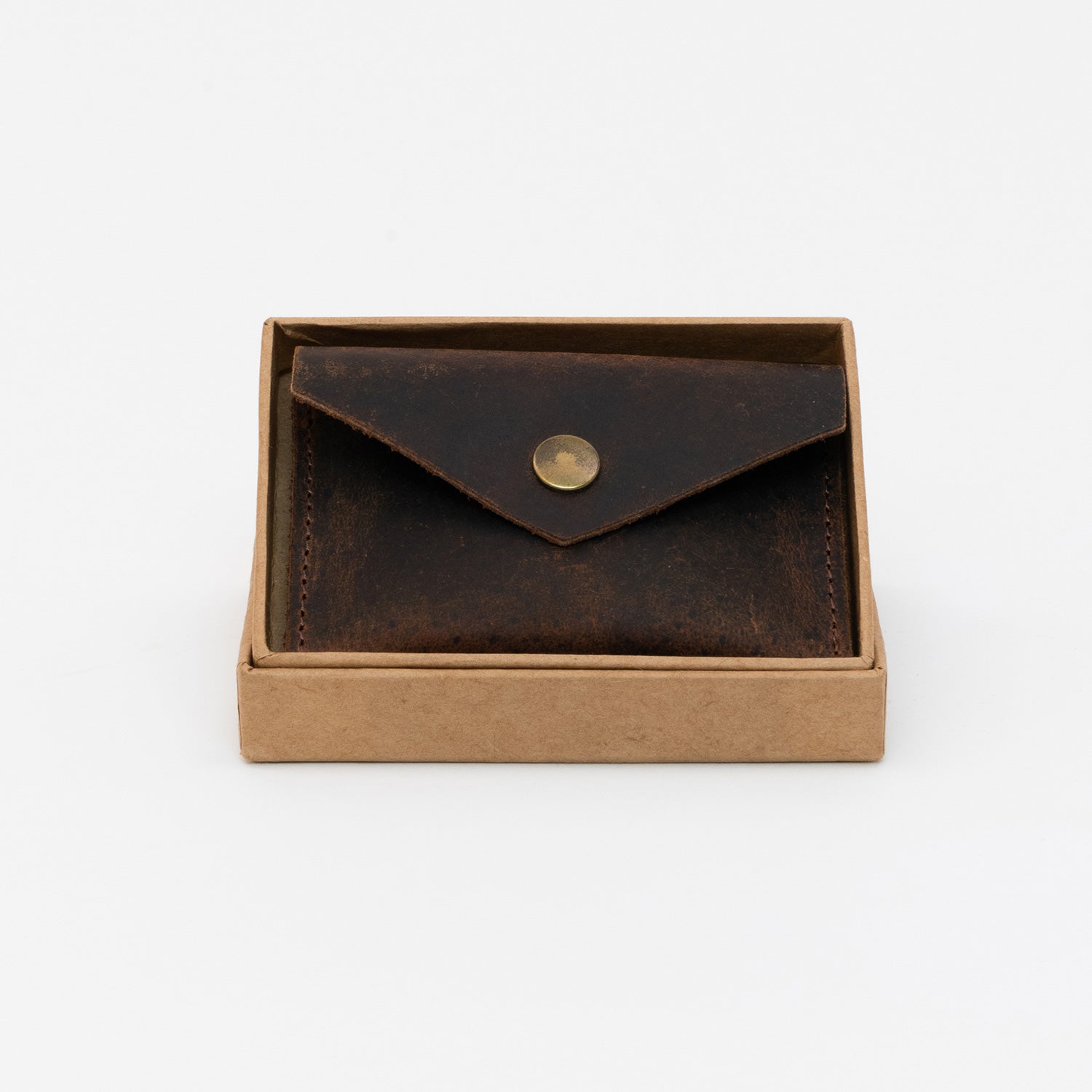Dark brown leather coin pouch with brass popper inside the tan box.