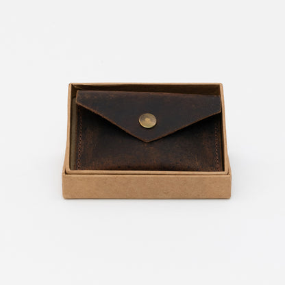 Dark brown leather coin pouch with brass popper inside the tan box.