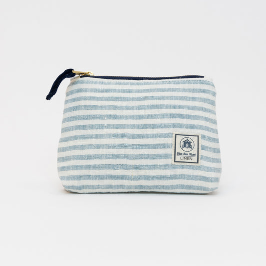 A photo of the small sea blue linen makeup bag on a white background. The bag has sea blue stripes and white stripes.