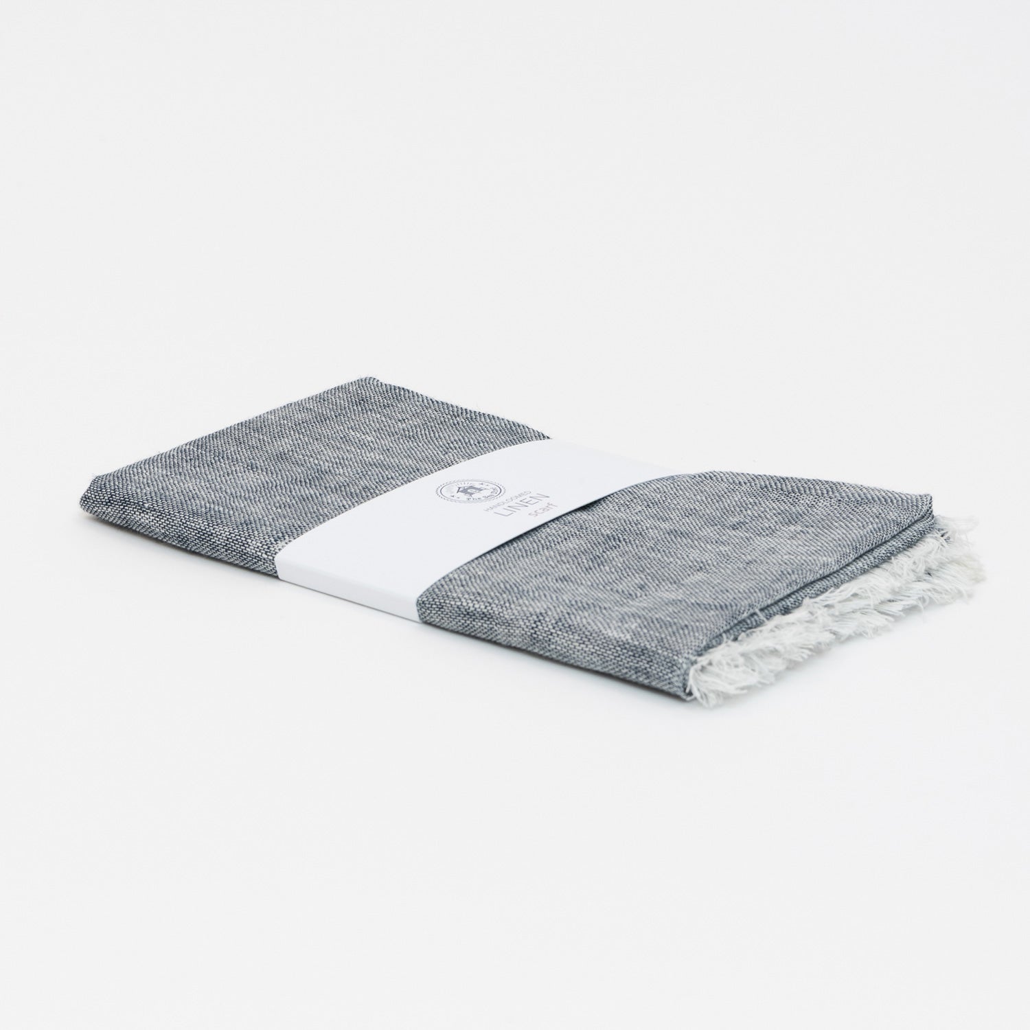 A photo of the linen denim blue scarf packaged and on a white background.