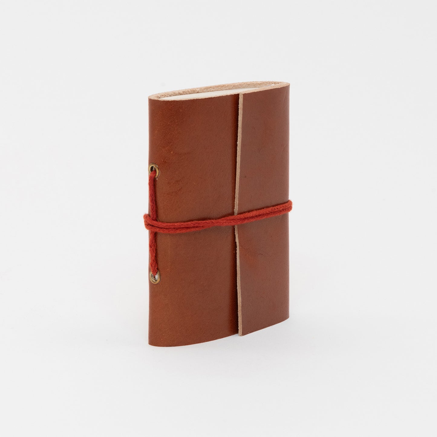 Side view of a tan leather bound journal with a leather tie around the middle.