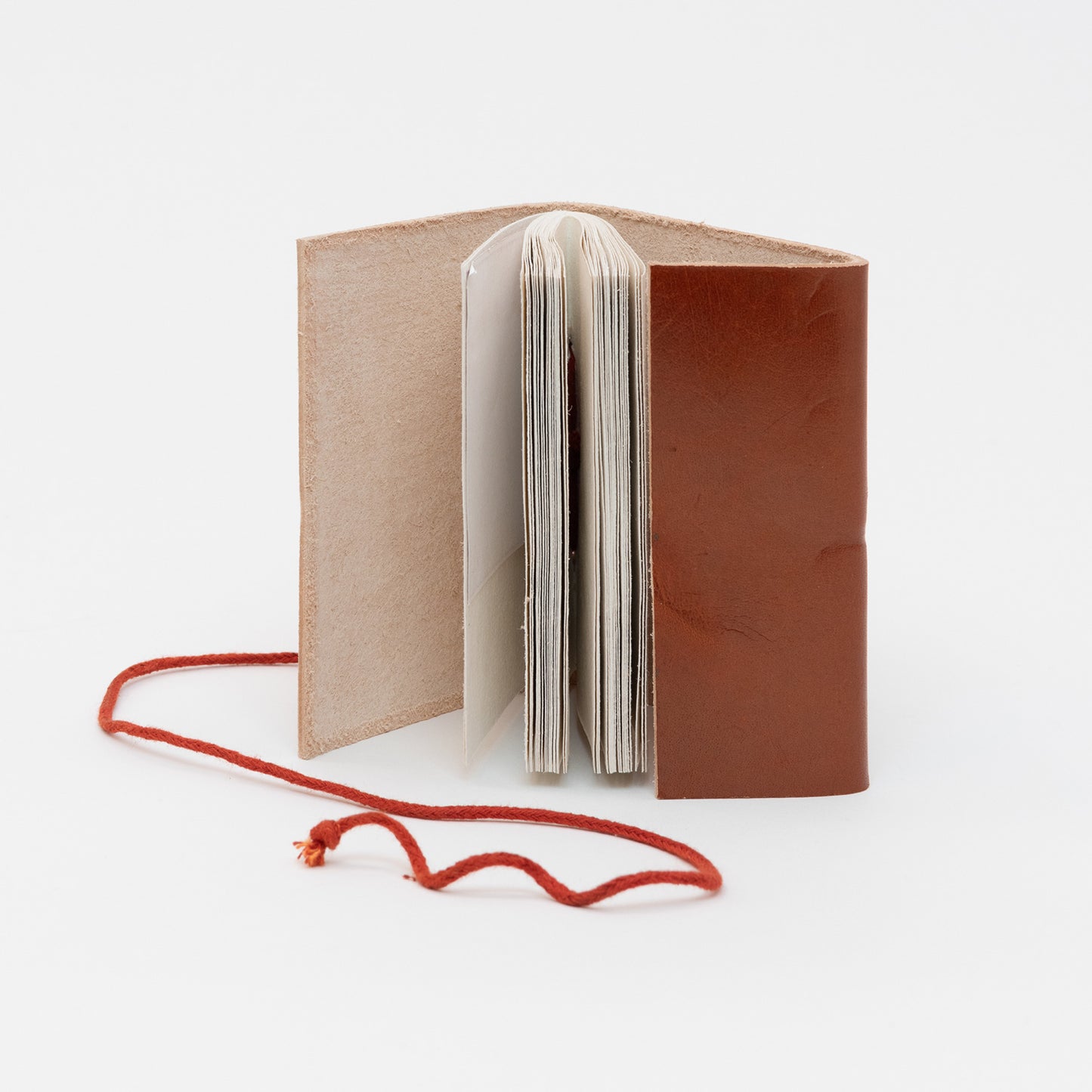 The small tan leather journal open on its side with unlined pages on view.