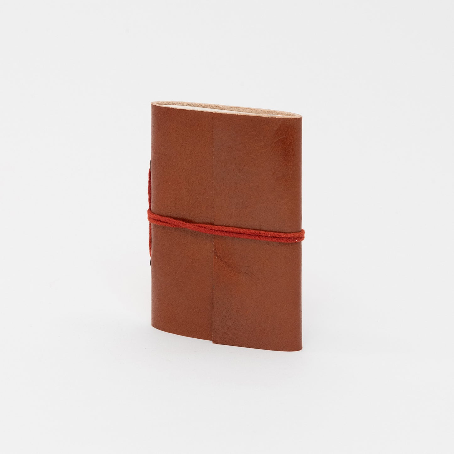 A tan leather bound journal with a leather tie around the middle.
