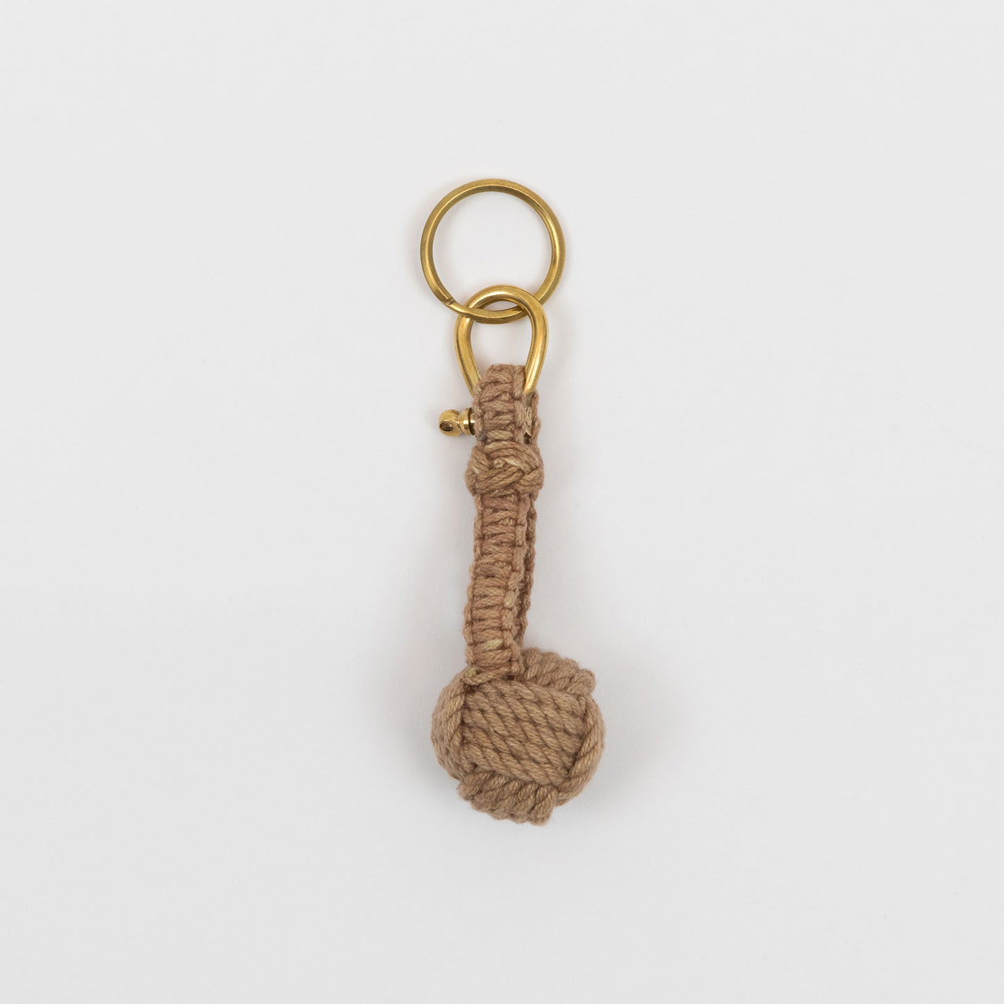 A monkey fish rope keyring, with brown rope and a gold ring, on a white background. 