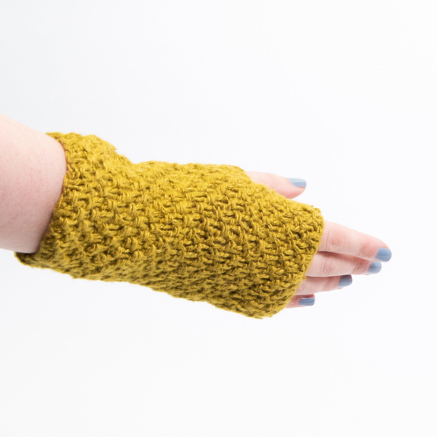 A mustard-yellow wristwarmer modelled on a hand, pictured on a white background.