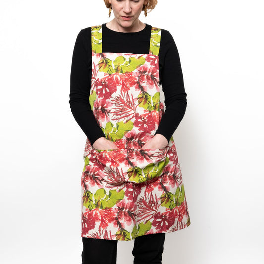 Model wearing a cross back apron in green and pink coloured seaweed design