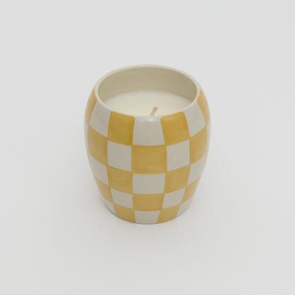Yellow and white checkerboard design ceramic pot with white candle.