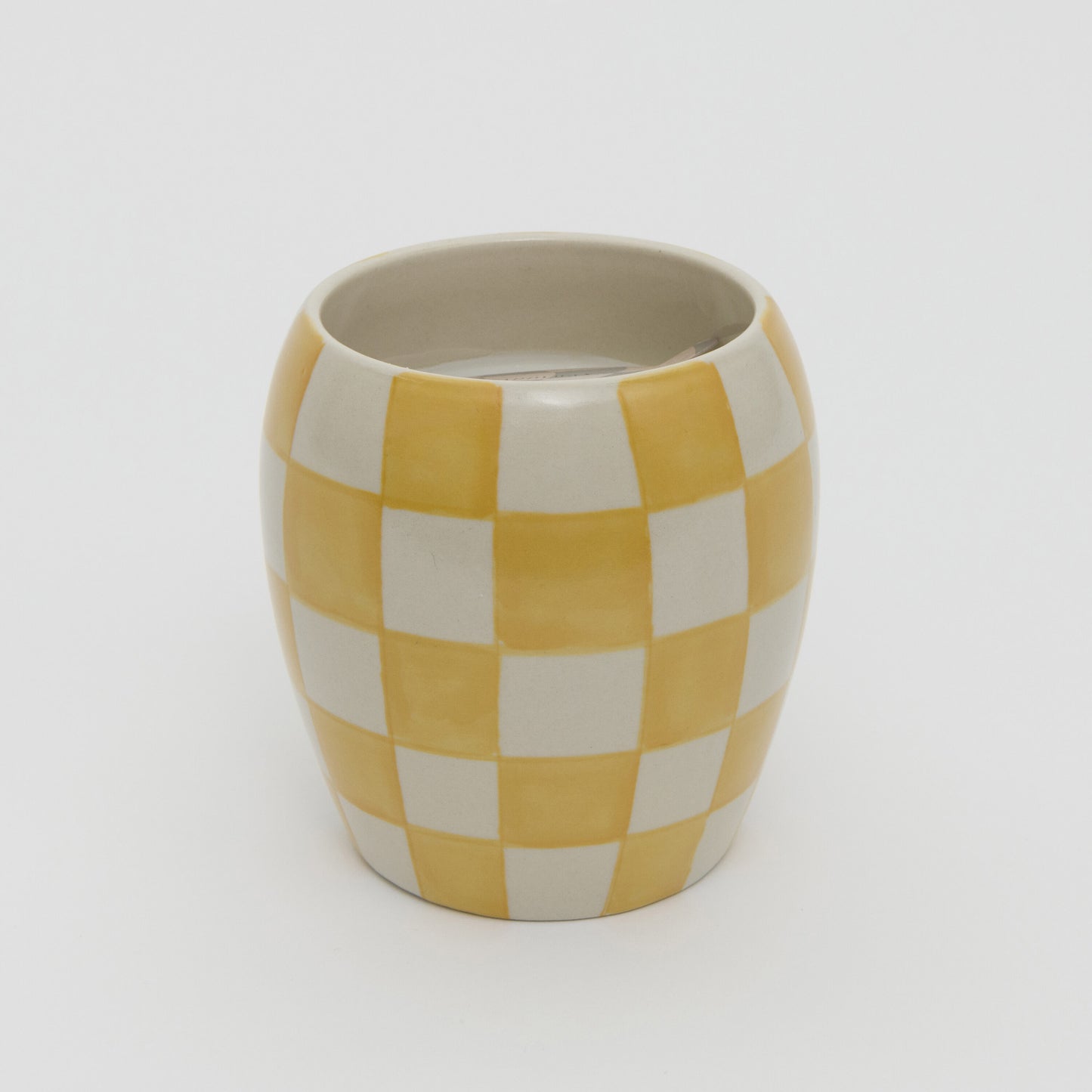 Yellow and white checkerboard design ceramic pot with white candle.
