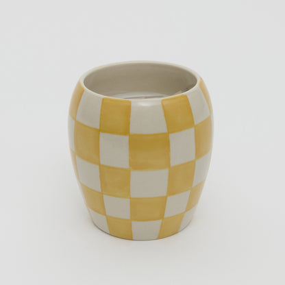 Yellow and white checkerboard design ceramic pot with white candle.