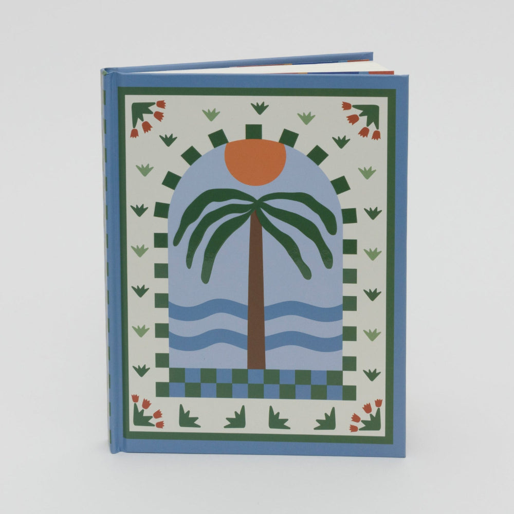 Front cover of a lined journal with the illustration of a palm tree, waves and sun in light and dark blue, green and cream with an orange sun.
