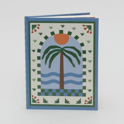 Front cover of a lined journal with the illustration of a palm tree, waves and sun in light and dark blue, green and cream with an orange sun.