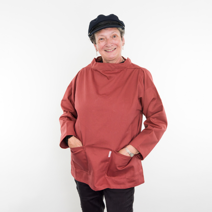 Person wearing a red smock and navy Breton cap on a white background
