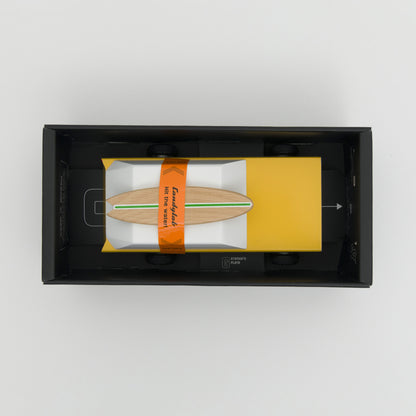 A photograph taken from above showing a yellow wooden toy car with wooden surfboard on its roof.