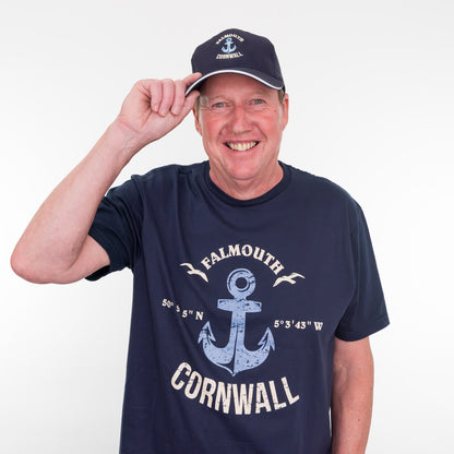 Man wearing a navy t-shirt with 'Falmouth Cornwall' design and matching cap on a white background