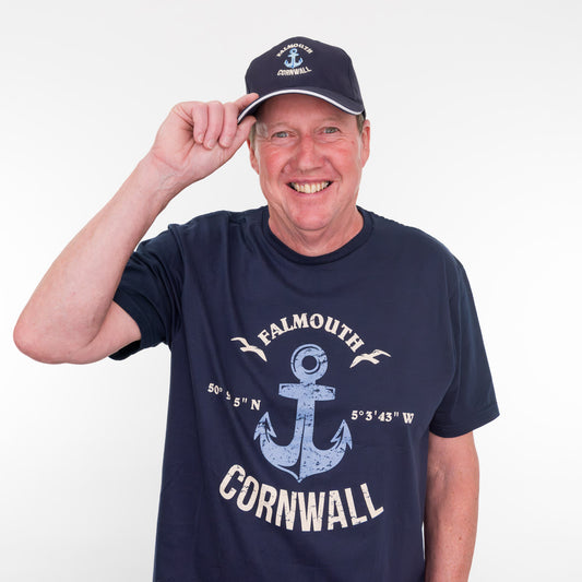 Man wearing a navy t-shirt with 'Falmouth Cornwall' design and matching cap on a white background