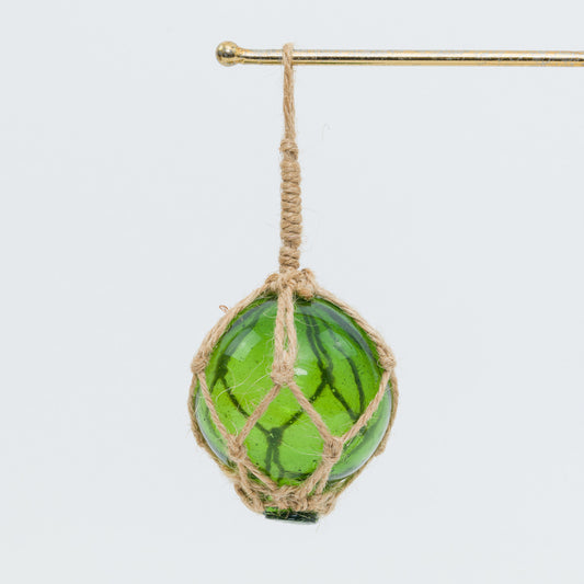 A green glass ball in rope net on a white background.